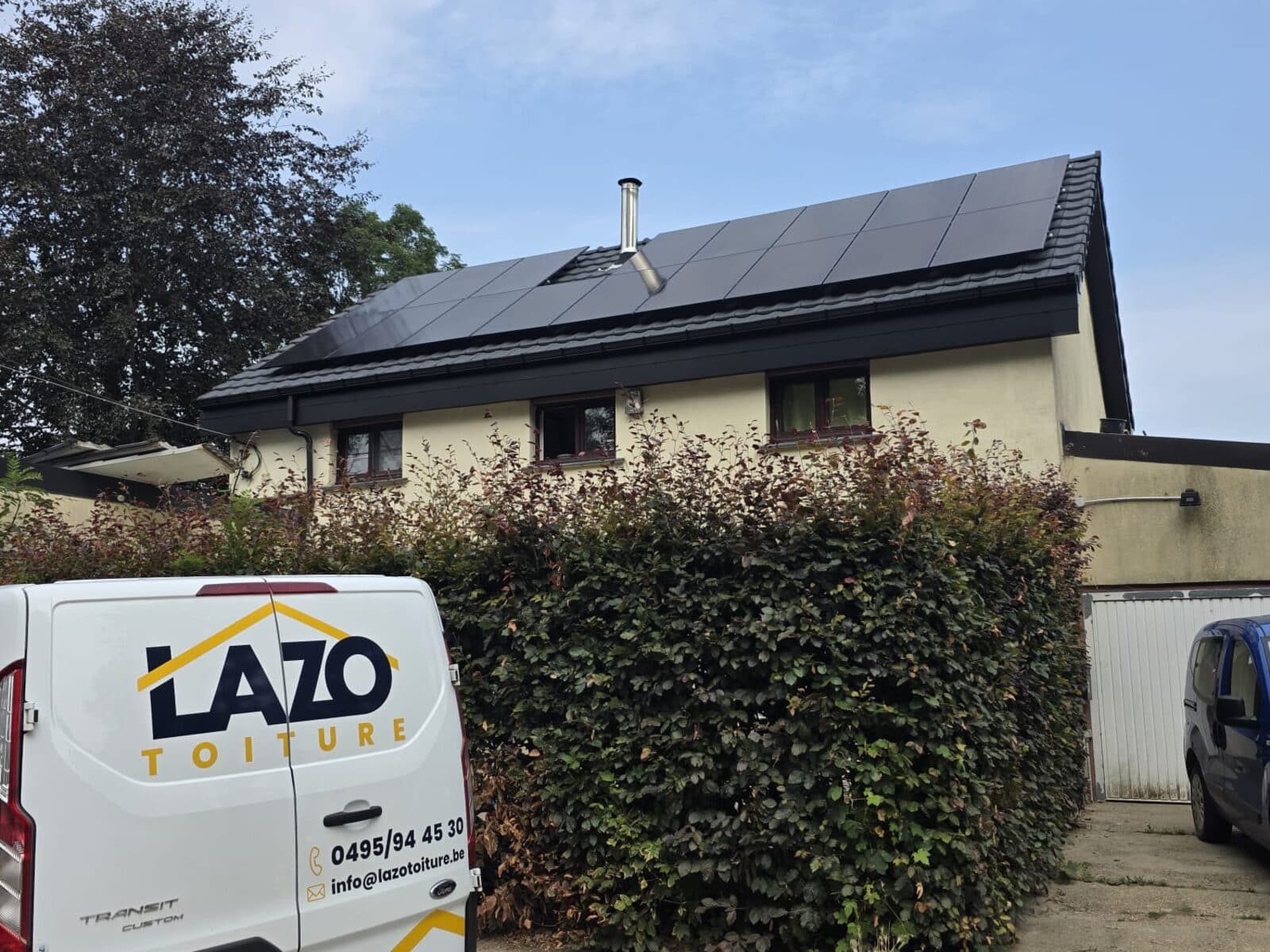 Deux couvreurs Lazo posant des panneaux photovoltaïques sur une toiture en tuiles