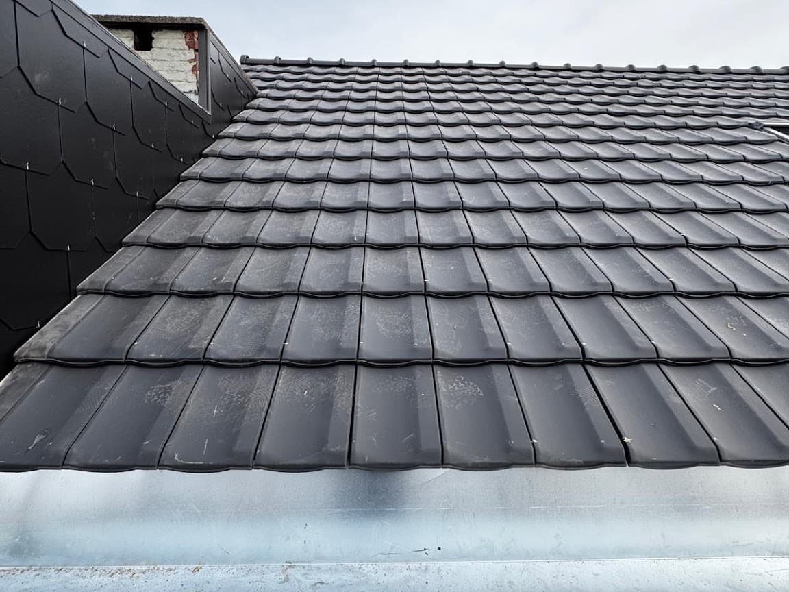 Toiture rénovée en tuiles anthracite, rive en ardoise et corniche en zinc neuve